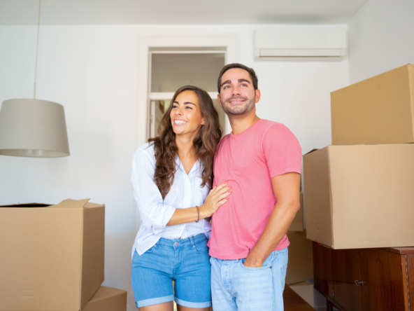 casal alegre olhando seu novo apartamento caminhando entre caixas de papelao e se abracando